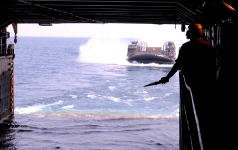 US Navy 110920-N-GH121-094 Boatswain's Mate 3rd Class Ronnie Guerra, from Union City, N.J., signals to operators aboard a landing craft air cushion
