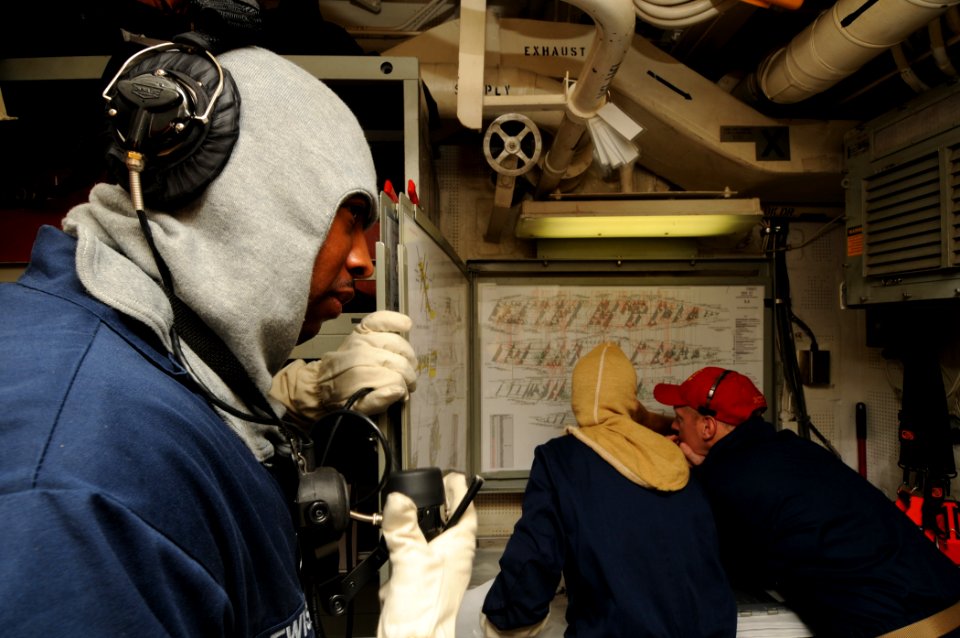 US Navy 110917-N-XQ375-058 Logistics Specialist 1st Class Calvin Lewis, left, communicates with the central control station