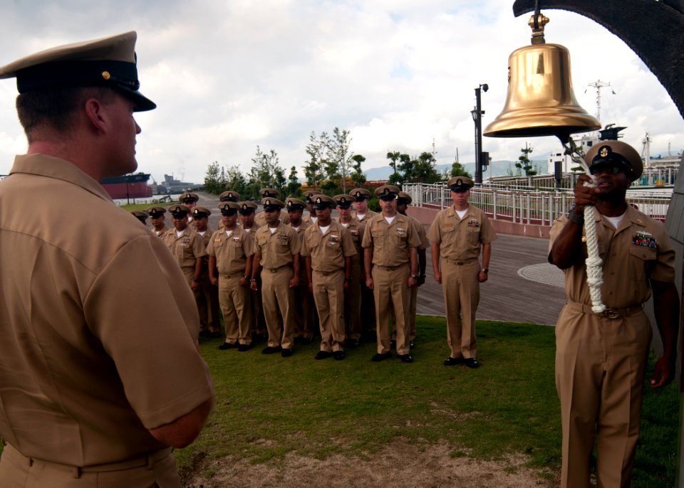 US Navy 110919-N-EA192-064 Chief Ship's Serviceman Warren Brown, right, rings a replica bell after the chief's mess aboard USS Mustin (DDG 89) dona
