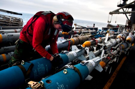 US Navy 110917-N-BT887-359 Aviation Ordnanceman Airman Nathan Blais, from Deluth, Minn., tightens the straps on a GBU-38 bomb aboard the Nimitz-cla