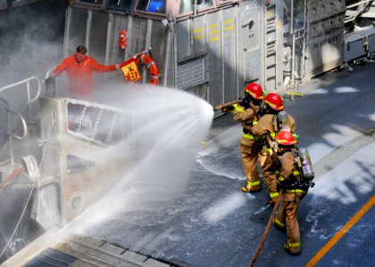 US Navy 110922-N-MW330-057 First responders use a fire hose to extinguish a simulated fire represented by two flags held by Damage Controlman 1st C