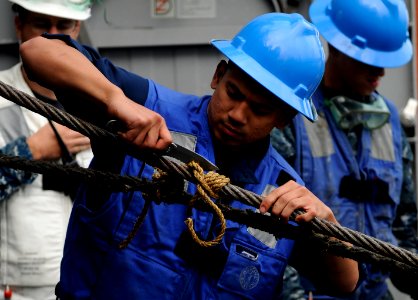 US Navy 110918-N-BC134-077 Seaman Phil Rocco cuts the line tied to a tension wire aboard the guided-missile cruiser USS Bunker Hill (CG 52) photo