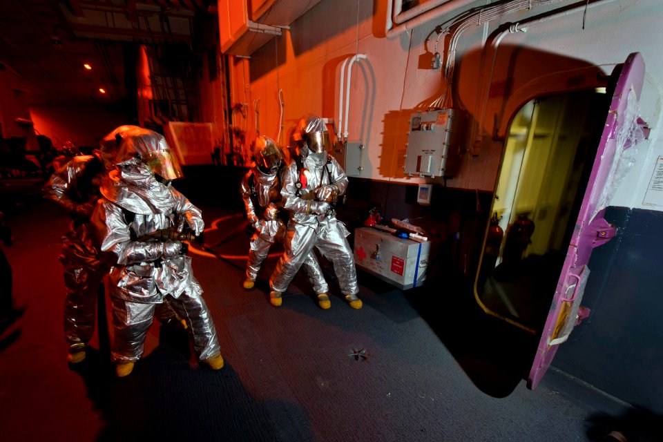 US Navy 110920-N-DR144-190 Air Department Sailors in hot suits fight a simulated fire in a hangar bay fuel station during a general quarters drill