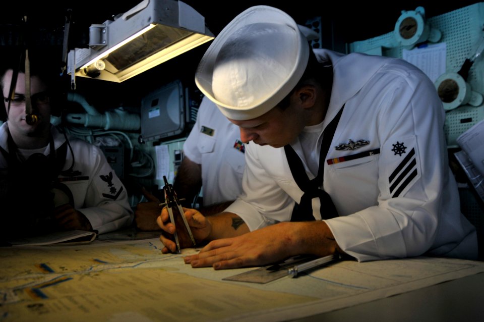 US Navy 110920-N-GW695-011 Quartermaster Seaman Edward Roth plots points on a navigational chart in the pilothouse aboard the amphibious transport