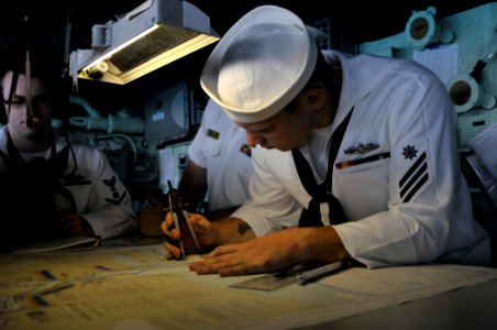 US Navy 110920-N-GW695-011 Quartermaster Seaman Edward Roth plots points on a navigational chart in the pilothouse aboard the amphibious transport