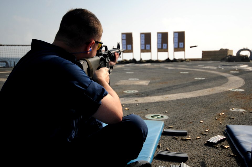 US Navy 110921-N-XQ375-483 Operations Specialist 1st Class Neil Belton fires an M16 rifle during a weapons qualification exercise aboard USS Mitsch