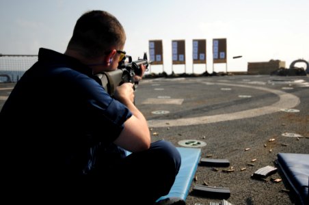 US Navy 110921-N-XQ375-483 Operations Specialist 1st Class Neil Belton fires an M16 rifle during a weapons qualification exercise aboard USS Mitsch
