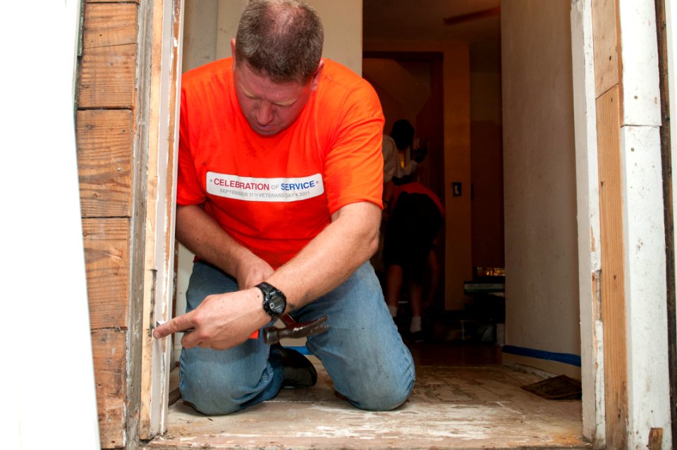 US Navy 110921-N-JK630-433 Master-at-Arms 1st Class Keith Thomas, assigned to Naval Medical Center Portsmouth, nails a piece of wood in a door fram