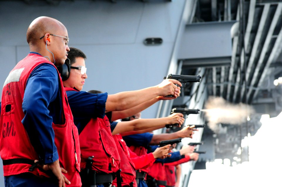 US Navy 110923-N-QL471-544 Chief Gunner's Mate Kenneth A. Coley, left, instructs Aviation Ordnanceman Airman Jesse J. Alonzo as he fires a 9mm pist