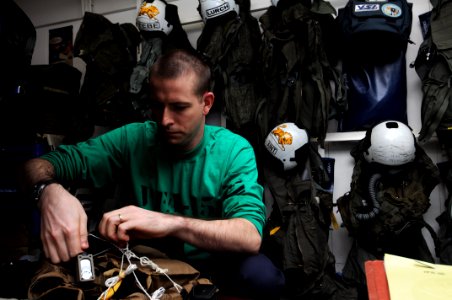 US Navy 110921-N-JD217-036 Aircrew Survival Equipmentman 1st Class Jason D. Seely performs maintenance on a pilot's survival vest aboard the aircra