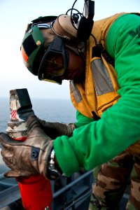 US Navy 110925-N-BT887-081 Aviation Boatswain's Mate (Equipment) 3rd Class Alonzo Bass inspects a hold-back bar before flight operations aboard the