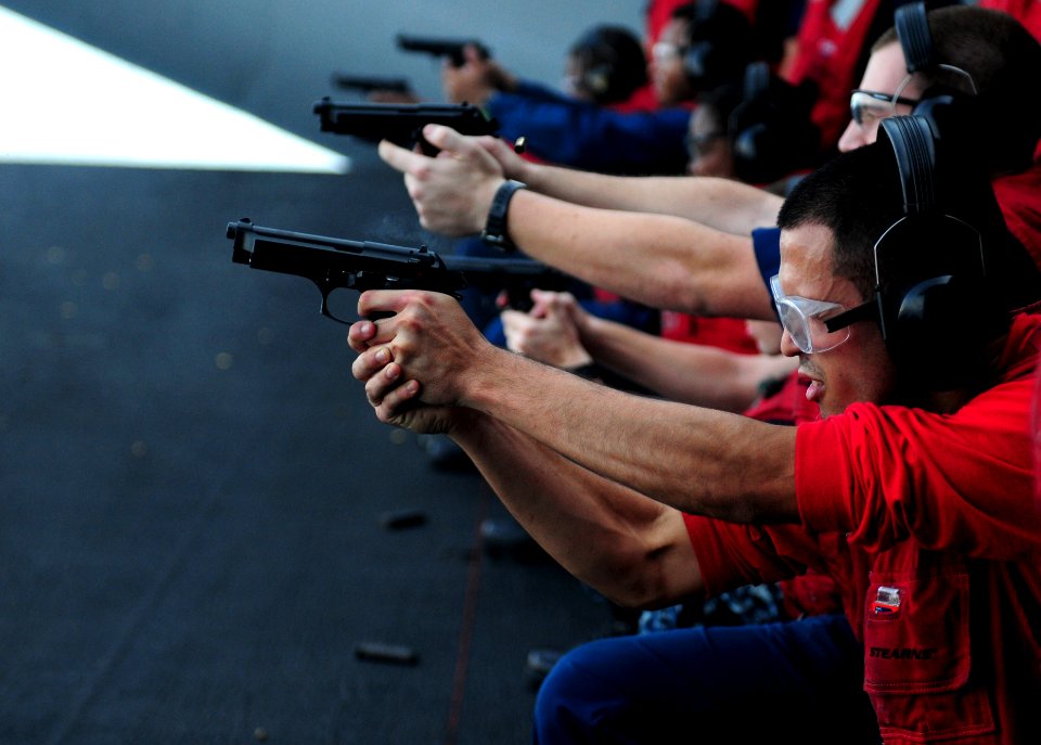 US Navy 110923-N-QL471-443 Aviation Ordnanceman 3rd Class John M. Tracey fires a 9mm pistol during a live-fire exercise on an aircraft elevator abo