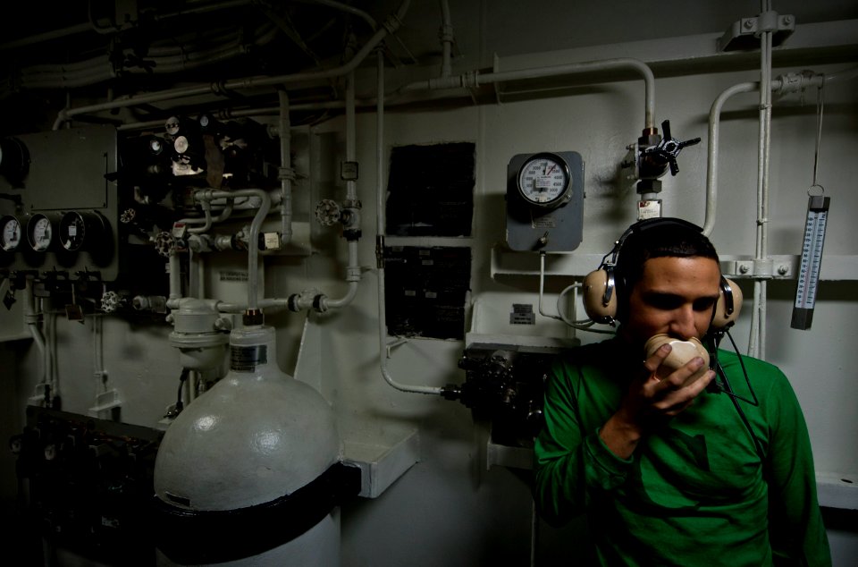 US Navy 110927-N-TU221-482 Aviation Boatswain's Mate (Equipment) Airman Antonio Esquivel uses a sound-powered telephone inside a retraction engine