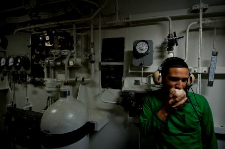 US Navy 110927-N-TU221-482 Aviation Boatswain's Mate (Equipment) Airman Antonio Esquivel uses a sound-powered telephone inside a retraction engine photo