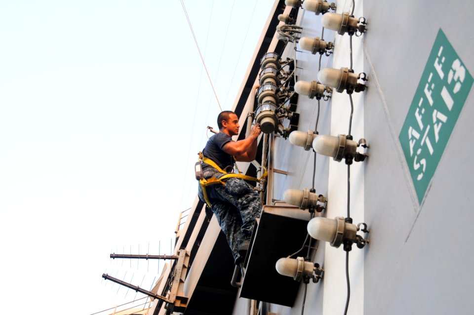 US Navy 110923-N-TU894-138 Electrician's Mate Fireman Martin U. Torres conducts maintenance on the rotary beacon on the island of the aircraft carr