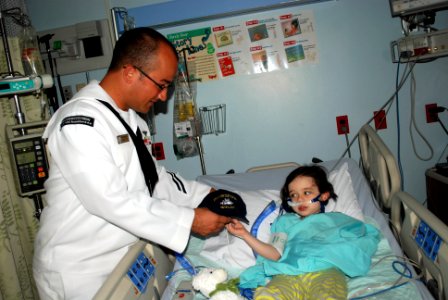 US Navy 110927-N-AU127-629 Aviation Electrician's Mate 2nd Class Anthony Barnardo, assigned to USS Constitution, gives a Navy ball cap to a patient