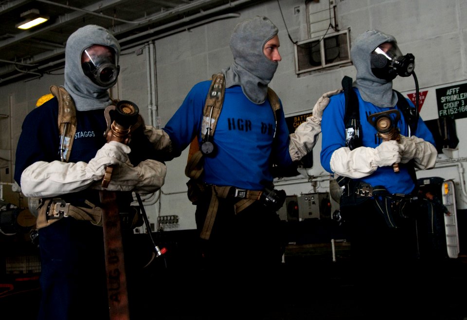US Navy 110927-N-JN664-005 Aviation Boatswain's Mate (Handling) Airman Joshua Bard, center, leads his hose team during a simulated fire drill in th