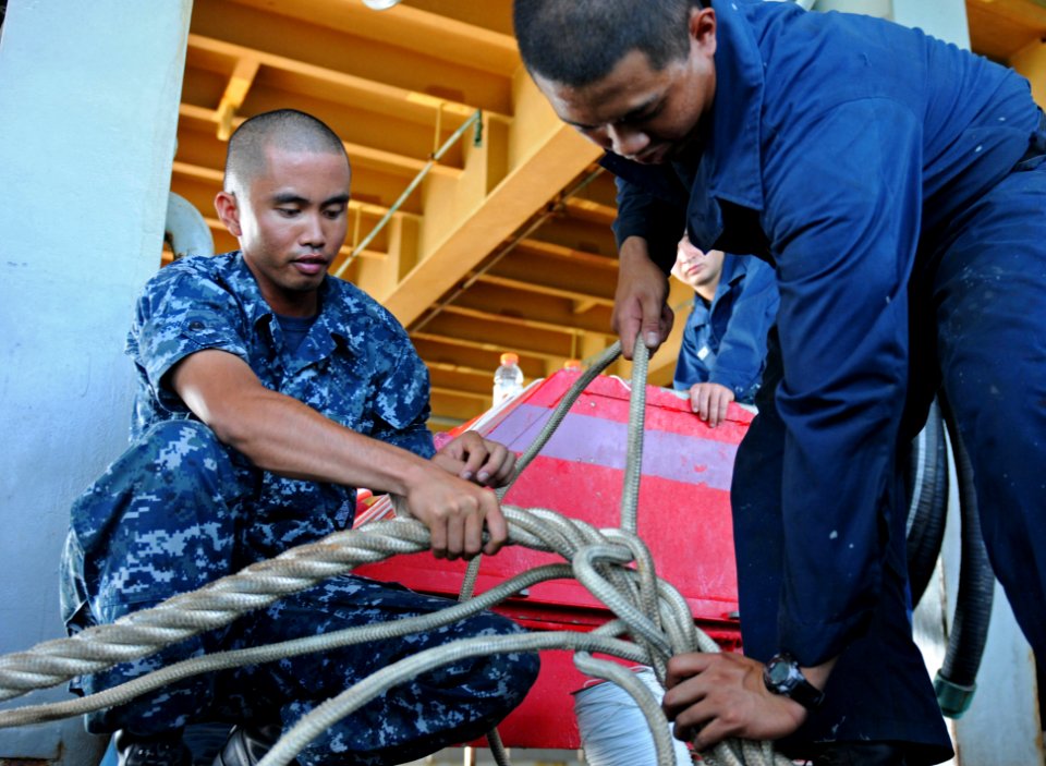 US Navy 110927-N-MW330-480 Boatswain's Mate 2nd Class Dennis Castro, left, and Boatswain's Mate Seaman Ulyses Morero splice a line aboard the forwa