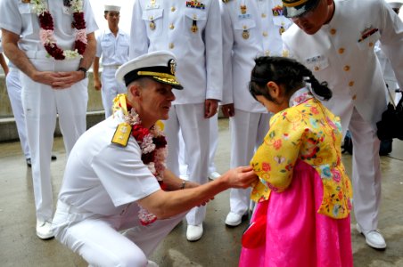 US Navy 110929-N-WW409-125 Rear Adm. J.R. Haley, commander of Task Force 70, presents a coin to a girl during a welcoming ceremony for the arrival