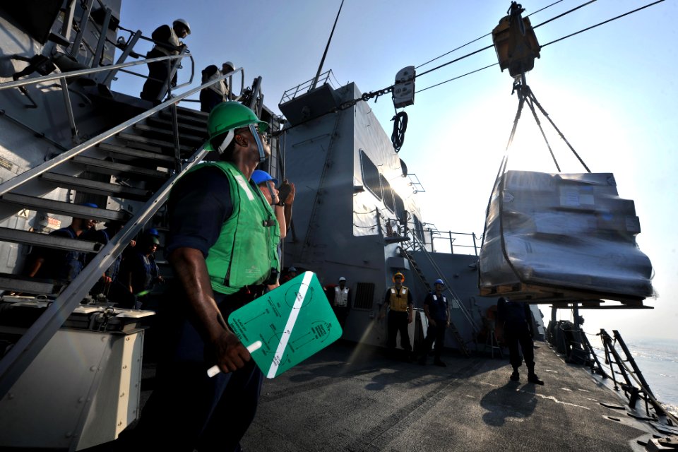 US Navy 110930-N-YZ751-071 Boatswain's Mate 3rd Class Carl-Evans Augustin stands by as a pallet of supplies is delivered aboard the guided-missile