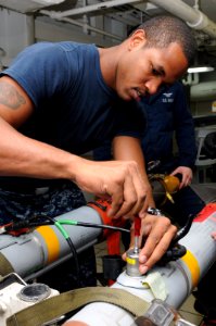 US Navy 111003-N-YC505-038 Aviation Ordnanceman 3rd Class Adrian T. Reddick attaches diagnostic cables to ordnance aboard the aircraft carrier USS