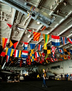 US Navy 111004-N-BT887-031 Boatswain's Mate 2nd Class Alex Armour, from Centralia, Mo., signals to raise a sliding padeye aboard the Nimitz-class