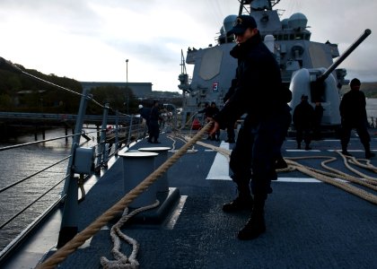 US Navy 111003-N-FI736-034 Logistics Specialist 3rd Class Hyeon hauls in a mooring line as the guided-missile destroyer USS Arleigh Burke (DDG 51)