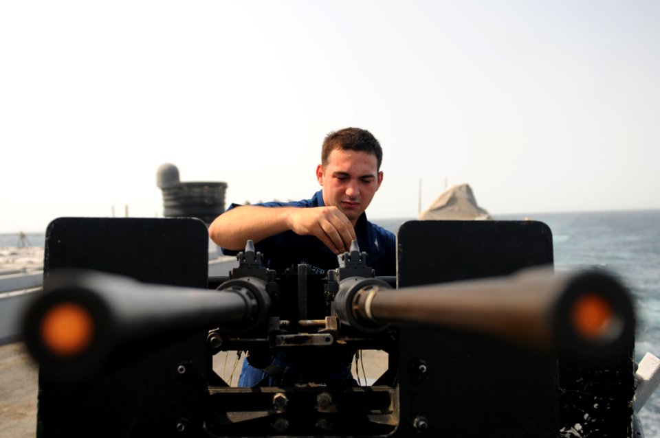 US Navy 111006-N-XQ375-033 Fire Controlman 3rd Class Dustyn Walker performs maintenance on a .50-caliber machine gun