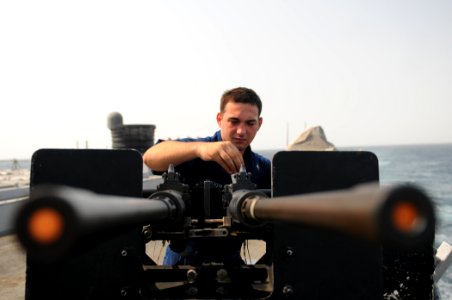 US Navy 111006-N-XQ375-033 Fire Controlman 3rd Class Dustyn Walker performs maintenance on a .50-caliber machine gun