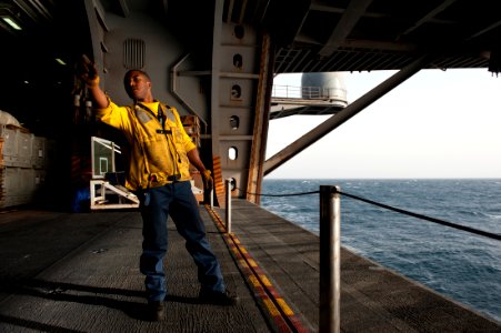 US Navy 111004-N-BT887-089 Aviation Boatswain's Mate (Handling) 3rd Class Marlon Squires, from Stockton, Calif., signals to lower an aircraft eleva