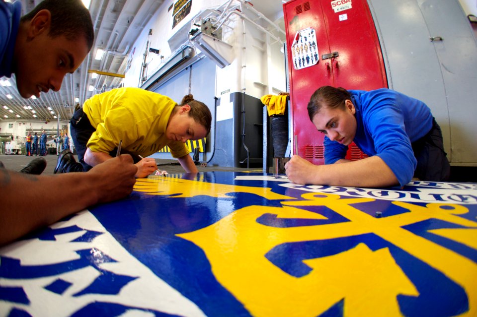 US Navy 111004-N-ZC343-090 Sailors assigned to V3 division aboard the amphibious assault ship USS Bonhomme Richard (LHD 6) finish painting a sign w