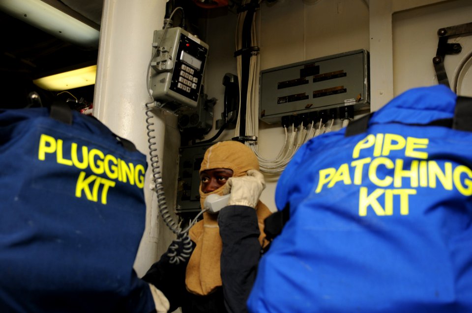 US Navy 111008-N-XQ375-010 Ship's Serviceman 2nd Class Bawa Lengani communicates with a repair locker on an integrated voice communications system