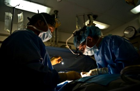 US Navy 111010-N-GC412-458 Hospital Corpsman Seaman Tommy Maez, left, assists Lt. Cmdr. Julie Dierksheide with a suture after an abdominal surgery photo