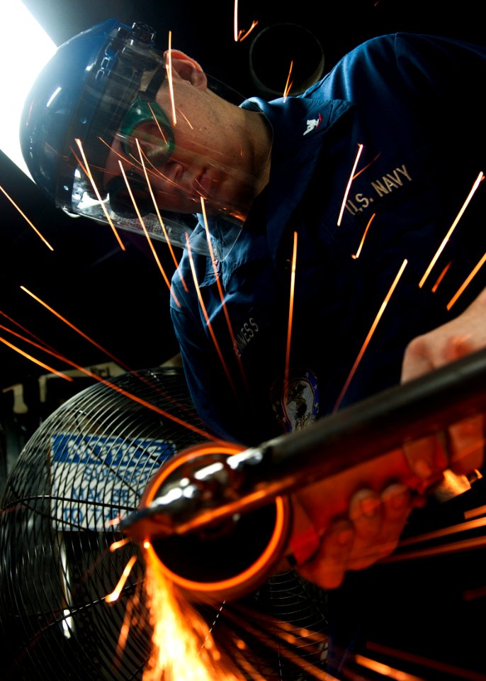 US Navy 111011-N-BT887-330 Hull Maintenance Technician 3rd Class Jeffrey Meginness, from Modesto, Calif., grinds a hatch stanchion aboard the Nimit