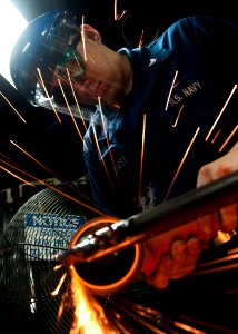 US Navy 111011-N-BT887-330 Hull Maintenance Technician 3rd Class Jeffrey Meginness, from Modesto, Calif., grinds a hatch stanchion aboard the Nimit