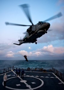 US Navy 111010-N-FI736-401 A Royal Navy HM MK 1 Merlin helicopter picks up a Royal Marine with a winch from the flight deck of guided-missile destr
