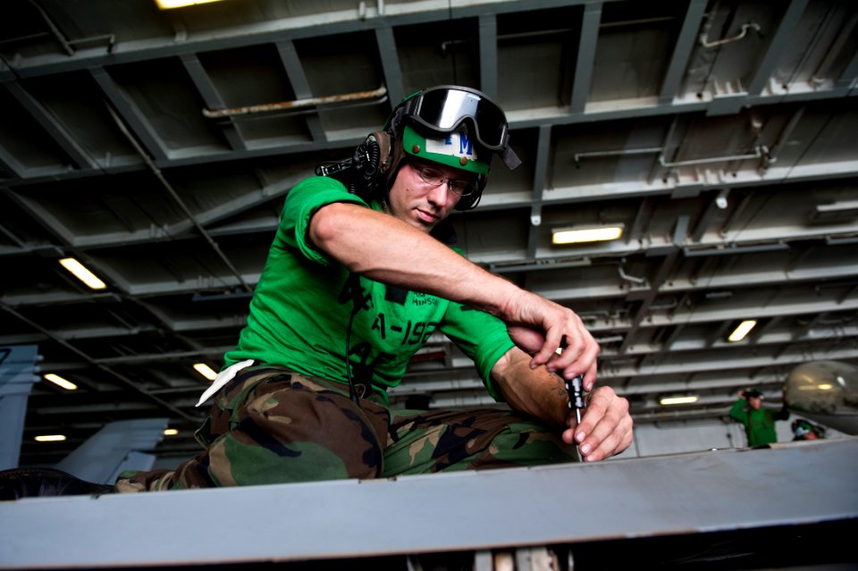 US Navy 111012-N-BT887-201 Aviation Structural Mechanic 2nd Class Michael Hinson, from Pineville, N.C., removes a fastener from the wing of an F-A