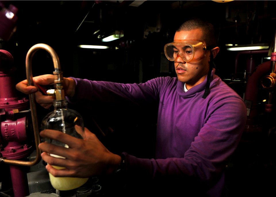 US Navy 111012-N-RJ456-056 Aviation Boatswain's Mate (Fuel) Airman Jonah Aficial, a San Diego native, gathers a sample of fuel to test for purity i