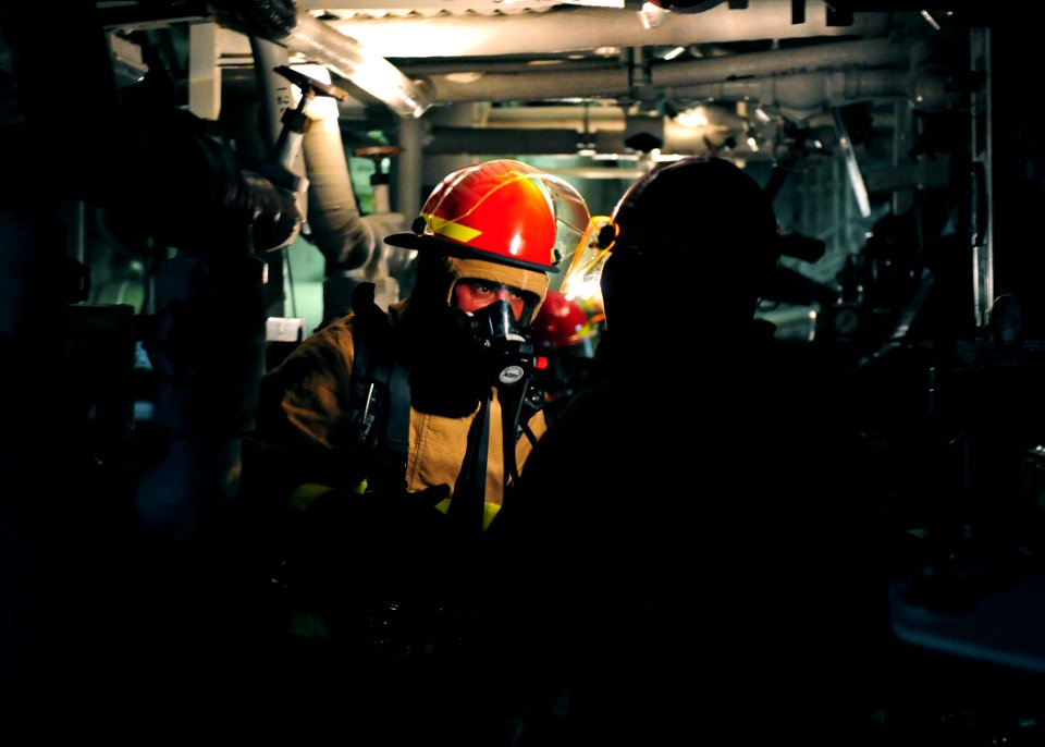 US Navy 111011-N-ED900-453 Fire assessment team members discuss the proper route to take while searching for a simulated fire in a main engine room