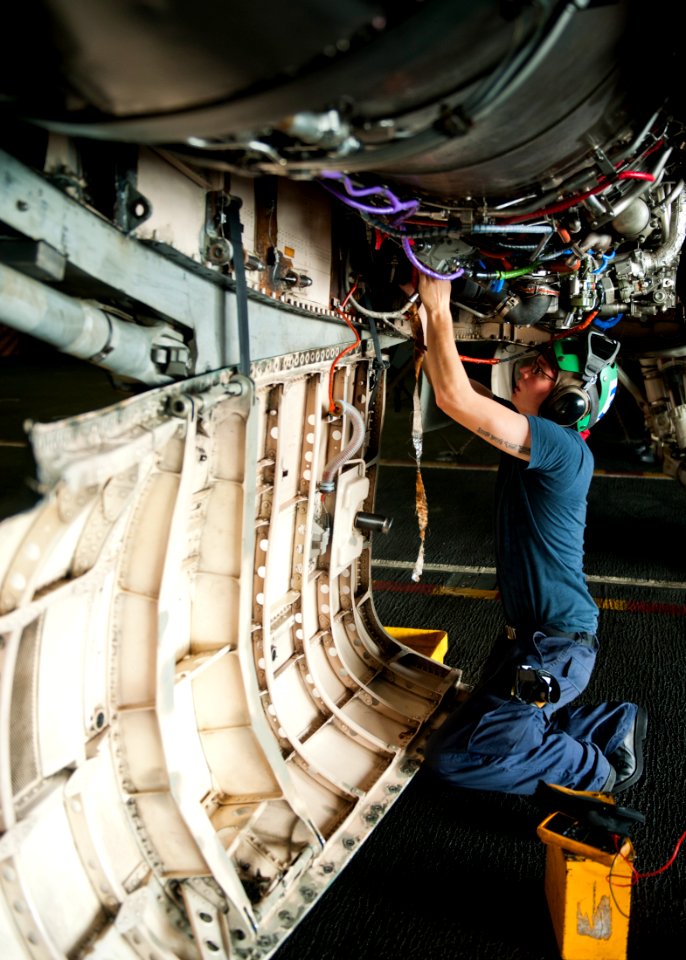 US Navy 111012-N-BT887-217 Aviation Electrician's Mate Airman Michael Sawyer performs maintenance on the engine of an F-A-18C Hornet