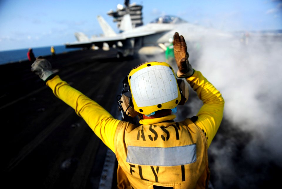 US Navy 111012-N-VN693-320 Aviation Boatswain's Mate Airman Michael Nicholas directs an F-A-18F Super Hornet assigned to the Black Aces of Strike