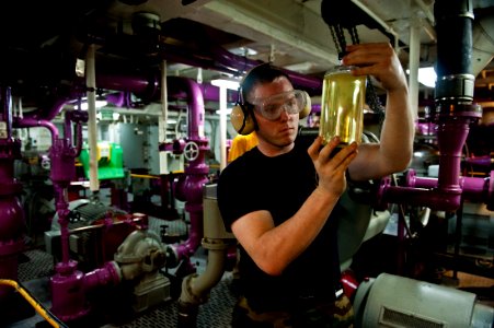 US Navy 111012-N-BT887-329 Aviation Boatswain's Mate (Fuel) 3rd Class James Hiatt checks a fuel sample for clarity during fuel purification