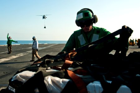 US Navy 111013-N-BT887-308 Logistics Specialist Seaman Robert Marlin unwraps cargo during a vertical replenishment aboard the Nimitz-class aircraft