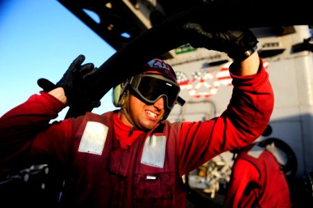 US Navy 111016-N-VN693-238 Aviation Ordnanceman 2nd Class Matthew Timour, from Wallingford, Conn., lifts a fuel line out of the way while storing o