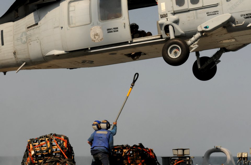 US Navy 111012-N-XQ375-403 Boatswain's Mate Seaman Lucio Robles, left, and Seaman Matt Binnie attach a cargo net to an MH-60S Sea Hawk helicopter