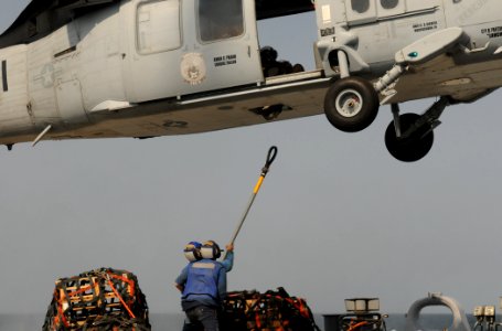 US Navy 111012-N-XQ375-403 Boatswain's Mate Seaman Lucio Robles, left, and Seaman Matt Binnie attach a cargo net to an MH-60S Sea Hawk helicopter