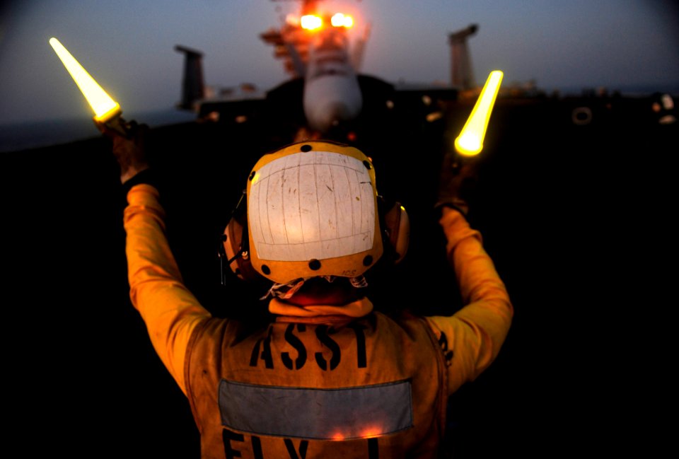 US Navy 111016-N-VN693-648 Aviation Boatswain's Mate (Handling) Airman Michael Nicholas directs an F-A-18F Super Hornet assigned to the Black Aces