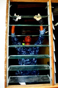 US Navy 111012-N-JH293-069 Ship's Serviceman Seaman Valexia Coleman places glass into a window frame during a Habitat For Humanity community servic