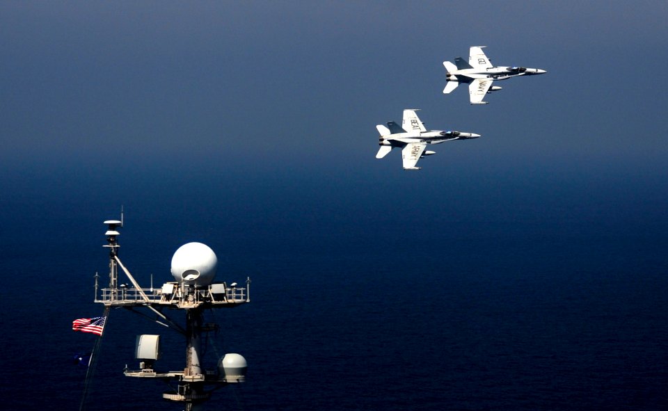 US Navy 111017-N-VN693-553 wo F-A-18C Hornets assigned to the Golden Dragons of Strike Fighter Squadron (VFA) 192 fly over the aircraft carrier USS