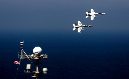 US Navy 111017-N-VN693-553 wo F-A-18C Hornets assigned to the Golden Dragons of Strike Fighter Squadron (VFA) 192 fly over the aircraft carrier USS